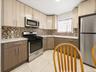 Kitchen featuring two-tone cabinetry with stainless steel hardware, a mosaic tile backsplash, white countertops, and white tile flooring