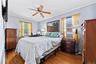 Bedroom 3 - featuring wood-finish flooring, light blue walls, a ceiling fan with integrated lighting, and two windows with blinds