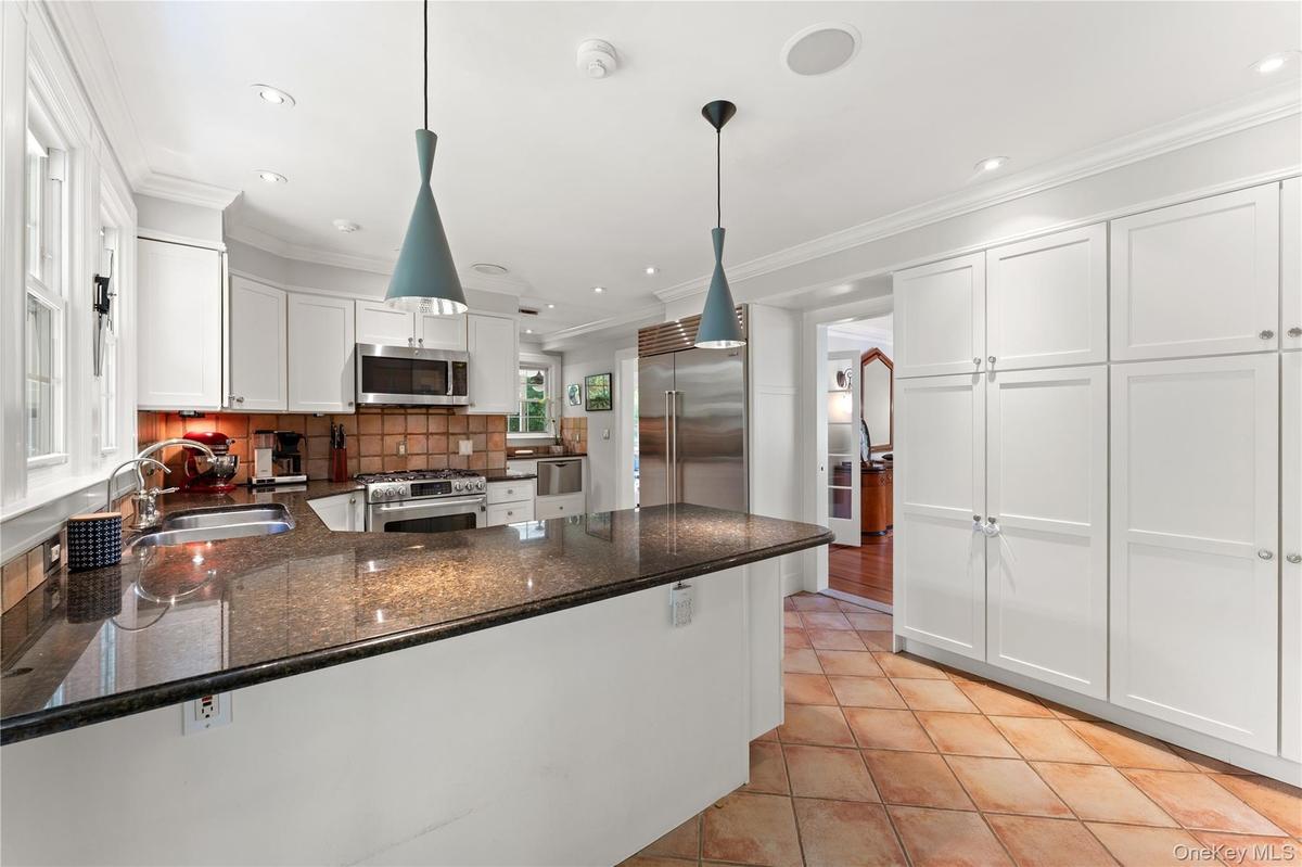 Dine-In Kitchen featuring stainless steel appliances, granite countertops, two sinks, custom cabinetry and access to the yard via  the French Door.