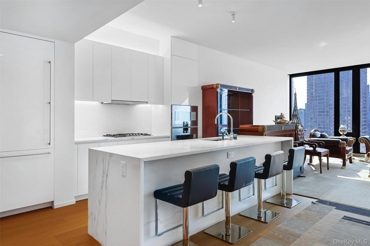 Contemporary kitchen featuring  custom Italian white lacquer cabinetry, Calacatta Lincoln marble countertops, natural stone finishes, and a full suite