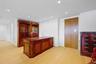Recessed lighting illuminates wood-finish flooring and a built-in wall unit with glass-front cabinetry