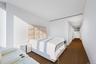 Bedroom featuring an upholstered headboard, white walls, wood-finish flooring, recessed lighting, and a linear ceiling light fixture