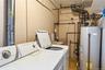 Utility area featuring a top-load washing machine, a water heater, a utility sink, exposed piping, and a large metal duct