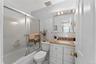 Bathroom featuring a shower/tub combination with sliding frosted glass doors, a vanity with a light-colored countertop and integrated sink, a mirrored