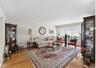Spacious living area featuring polished wood-finish flooring, ample natural light from large windows, and neutral wall tones