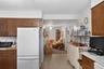 Galley kitchen featuring wood-finish cabinetry, white appliances, and a tiled floor