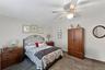 Carpeted bedroom featuring a ceiling fan with integrated lighting, a dark wood-finish armoire, and a rounded wall mirror