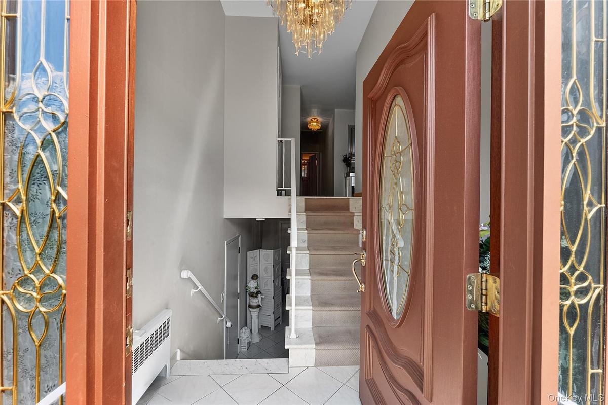 Entry foyer with tiled flooring and a multi-level staircase featuring white risers and handrails