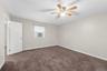 Spacious room featuring neutral wall tones, brown carpeting, a window with horizontal blinds, and a ceiling fan with light fixture