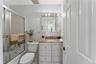 Bathroom featuring a tub/shower combination with sliding glass doors, a vanity with a light-colored countertop, and a mirrored medicine cabinet with o