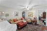 Living area featuring neutral wall paint, ceiling fan with integrated lighting, and carpet flooring
