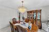 Dining area with a polished wood-finish table, a decorative chandelier, and light-toned walls