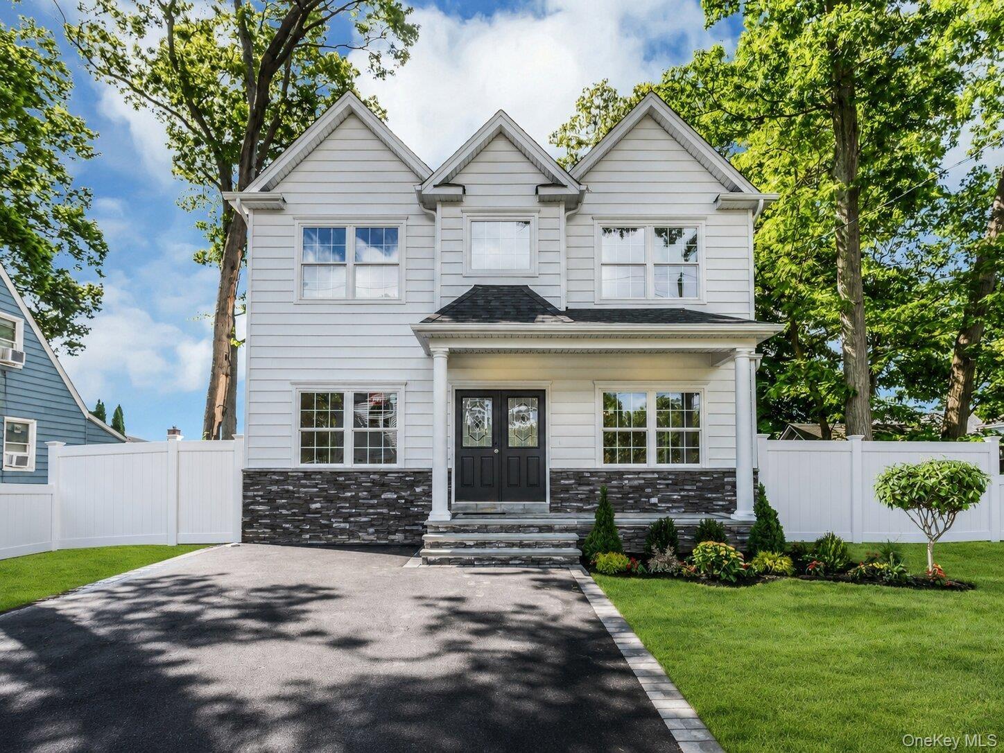 Colonial features: stacked stone detail front covered porch, asphalt double driveway, professionally landscaped with inground sprinklers