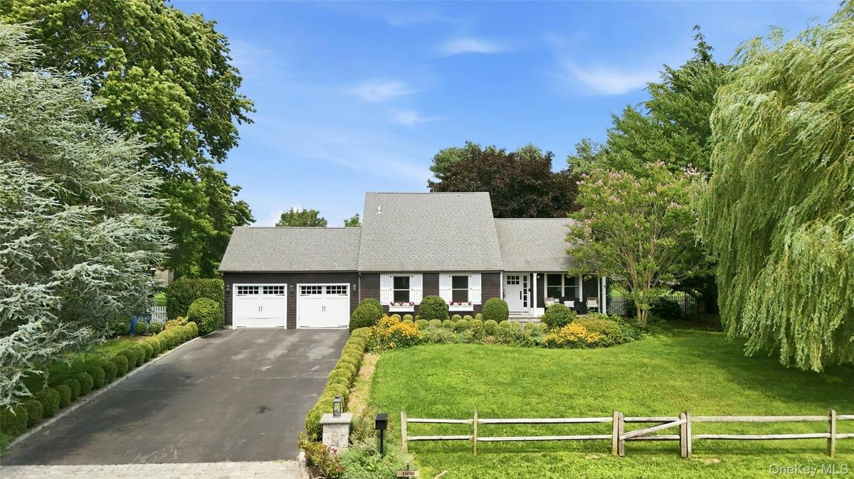 Exterior featuring a dark siding, white shutter accents, a gray shingle roof, and a two-car garage with white doors