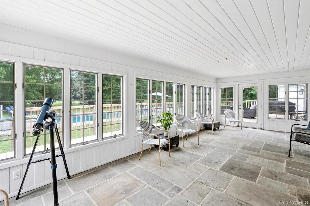 An expansive sun filled enclosed porch offering beautiful views of the surrounding landscape.