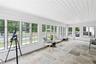 An expansive sun filled enclosed porch offering beautiful views of the surrounding landscape.