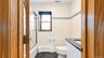 Bathroom featuring a white vanity with a dark speckled countertop, white tiled walls with a decorative border, black tile flooring, and a bathtub with