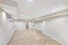 Spacious finished room featuring neutral-toned tile flooring, recessed lighting, and a window with a sheer curtain