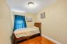 Room with light-toned walls, wood-finish flooring, a window with blue drapes, and an overhead light fixture