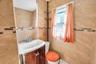 Bathroom featuring full-height tiled walls with a decorative accent band, a curved vanity with under-sink storage, a wall-mounted mirror, a single win