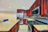 Kitchen featuring rich wood-finish cabinetry, light speckled countertops, stainless steel appliances, and a mosaic tile backsplash