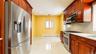 Galley kitchen featuring wood cabinetry, stainless steel appliances, recessed lighting, polished tile flooring, and light-toned countertops with match