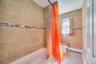 Bathtub with a tiled surround featuring a decorative mosaic accent band