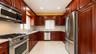 U-shaped kitchen featuring wood cabinetry, stainless steel appliances, speckled countertops, and a tile backsplash