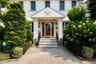Front entrance featuring a decorative wood-finish door, covered portico with fluted columns, and stone steps with wrought iron railings