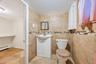 Ceramic tile walls with a decorative mosaic border complement the white vanity with integrated sink and chrome faucet