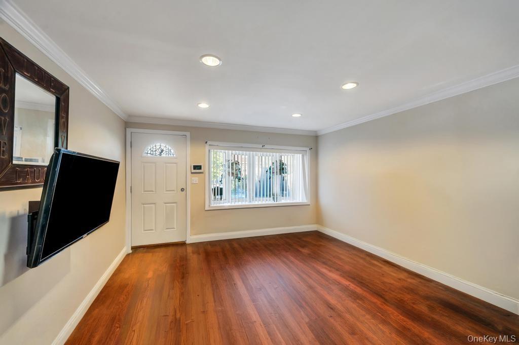 Spacious room featuring rich wood-finish flooring, recessed lighting, and crown molding
