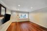 Spacious room featuring rich wood-finish flooring, recessed lighting, and crown molding