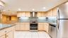 Kitchen featuring light wood cabinetry, stainless steel appliances, granite countertops, and tile flooring