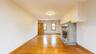 Expansive room featuring rich wood flooring, a decorative fireplace with a substantial stone surround and hearth, multiple windows, and a wood-panel d