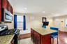 Kitchen featuring a gas range, stainless steel microwave, cherry wood-finish cabinetry, granite-style countertops, and a tile backsplash
