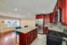 Open-concept kitchen with cherry wood cabinetry, granite countertops, and stainless steel appliances