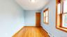 Room featuring wood-finish flooring, two windows with natural wood trim, a natural wood paneled door, baseboard heating, and a flush-mount ceiling lig