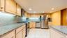 Kitchen featuring extensive light wood cabinetry, stone countertops, integrated stainless steel appliances, recessed ceiling lighting, and tiled floor