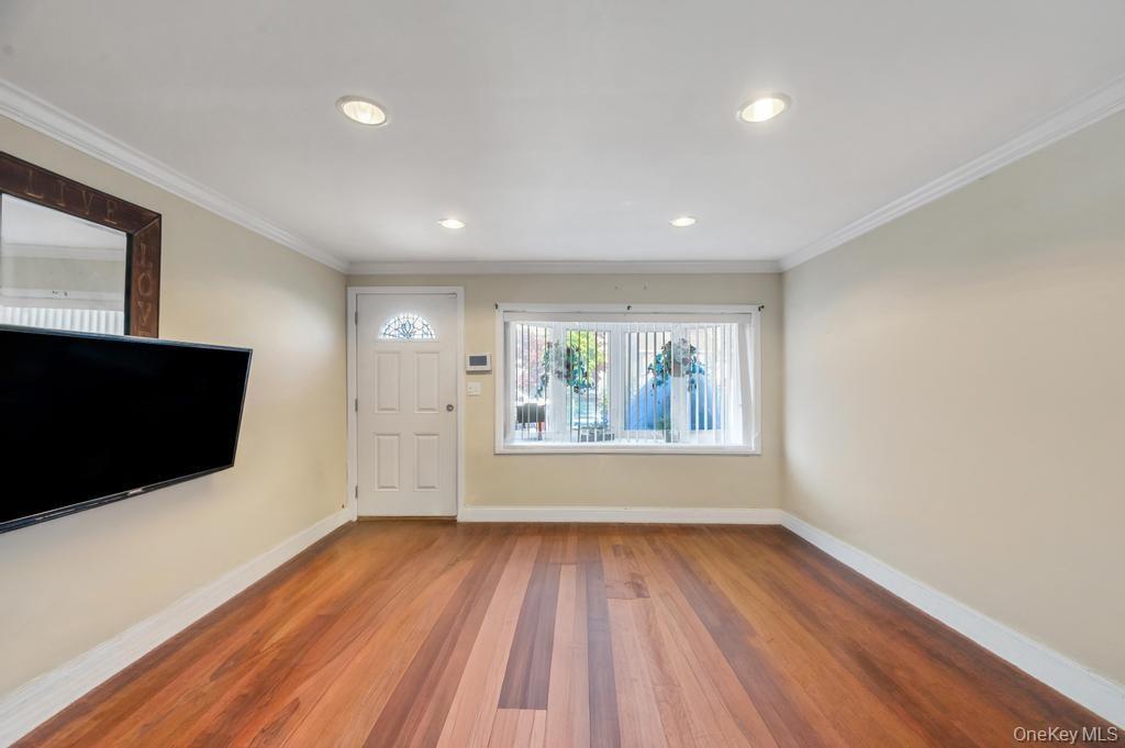 Spacious room featuring wood-finish flooring, recessed lighting, and crown molding