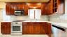 Kitchen featuring wood cabinetry, light-toned countertops, a full stainless steel appliance suite, and a tiled backsplash