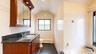 Bathroom featuring a dual-sink vanity with a dark countertop and wood-finish cabinetry, tiled walls, a bathtub with a dark surround, and a frosted win