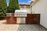 Outdoor kitchen featuring a built-in stainless steel grill, side burner, and storage cabinets, all integrated into a brick-clad island