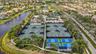 Extensive tennis and pickleball courts with perimeter fencing and abundant tropical landscaping