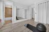 Room featuring wood-finish flooring, full-wall mirror, and a privacy curtain covering a built-in storage area