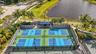Four outdoor pickleball courts with blue and light blue playing surfaces, surrounded by fencing