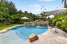 Curved swimming pool with a stone waterfall feature and integrated spa