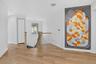 Expansive hallway with light wood-finish flooring, white walls, and a contemporary pendant light fixture