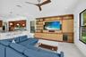Open concept living area featuring a custom media built-in with integrated lighting, wood-finish ceiling fan, and large windows
