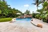 Resort-style pool with a rock waterfall feature, integrated spa, and a natural stone deck