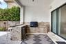 Outdoor kitchen featuring stone countertops, integrated sink, stainless steel under-counter refrigerator, and built-in storage drawers